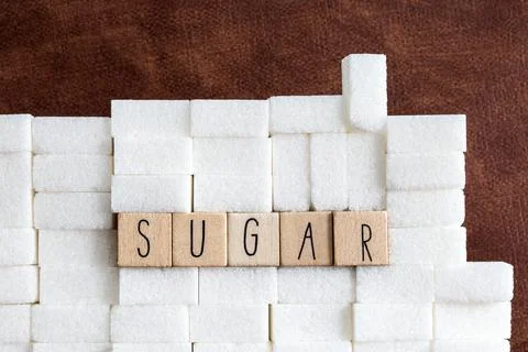 Sugar cubes wall with the text Sugar on brown natural background texture, Health Stock Photos