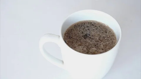 Sugar falling in a cup of coffee against a white background Stock Footage 76663826