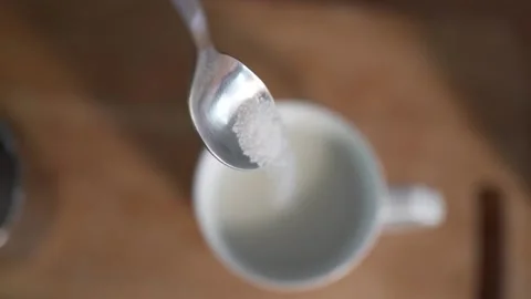 Sugar falling from spoon into cup with milk Stock Footage 131048619
