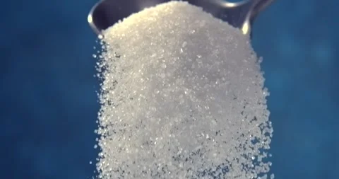 Sugar falling from a spoon in slow motion on blue background Stock Footage 346367495
