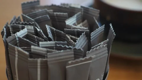 Sugar packets are neatly arranged in a spiral pattern on a table Stock Footage 317360382