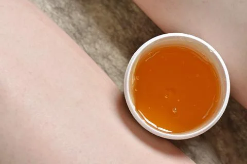 Sugar paste in a jar between the legs of a woman. Depilation Sugaring. Beauty Stock Photos