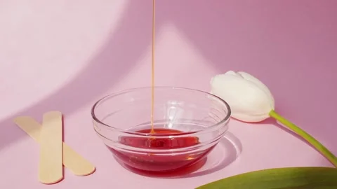 Sugar paste for shugaring flows down into a glass bowl on a pink background. Stock Footage 153101674