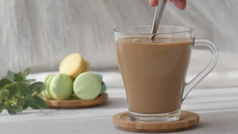 Sugar pouring from a spoon into cup of coffee with milk. Adding sugar to coffee Stock Footage 176799097