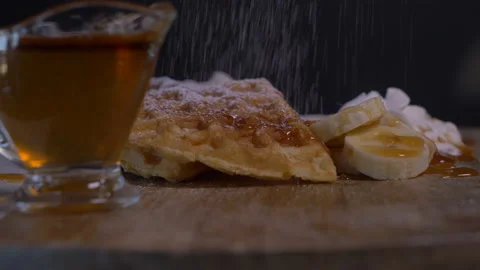 Sugar Sprinkles falling on Belgian Waffles, Maple Syrup, Banana Slices a Video stock 130791193