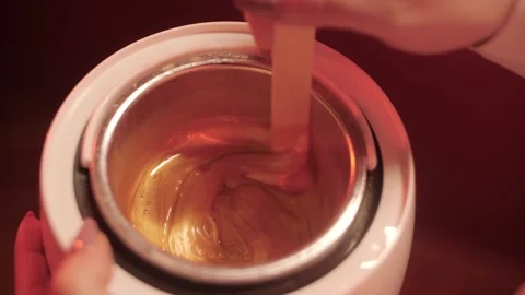 Sugaring specialist stirs sugar paste with a stick on a blue background Stock Footage 321002695