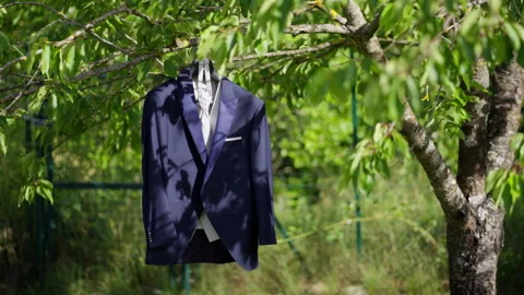 Suit Jacket and Shirt Hanging on Tree Branch in Sunlit Garden Setting Stock Footage 337579882