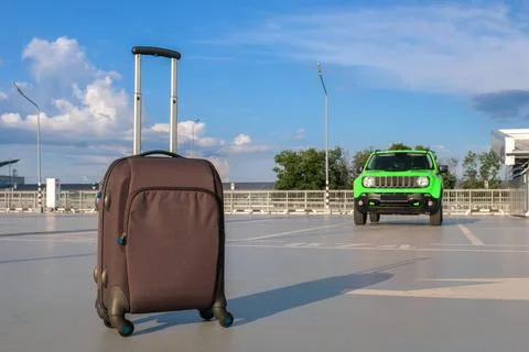 Suitcase on the background of a car in an open parking lot. Vacation concept Stock Photos