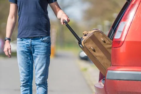Suitcase in hand, the young man pulled from the trunk passenger automobile Foto stock