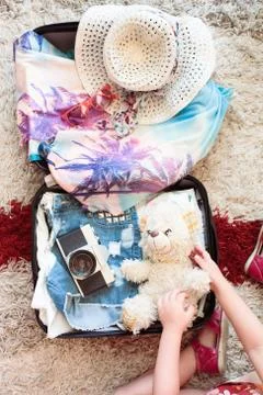 Suitcase with packed summer clothes, a camera, a hat and sunglasses Stock Photos