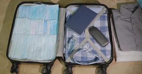 A suitcase with things and the may of protective masks. Paranoid collects things Foto stock