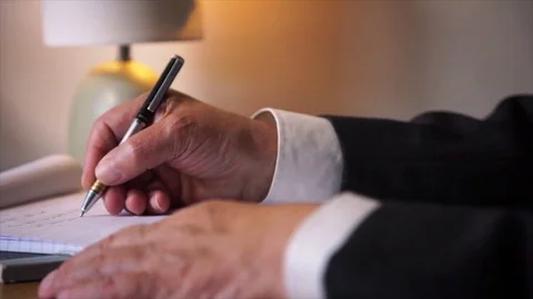 A suited man scribbles on a notepad with a calligraphy pen Video stock 77038440