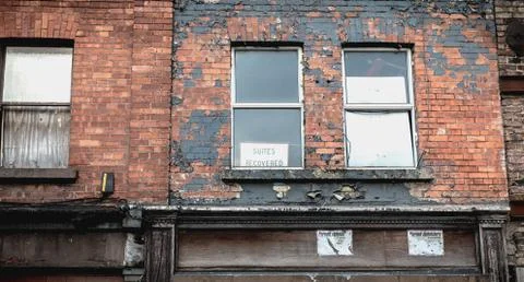 Suites recovered on a panel behind the window of an old dilapidated downtown  Stock Photos