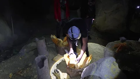 Sulfur Miner in Gas Mask Loading Heavy Yellow Mineral Chunks at Mount Ijen Stock Footage 333798916