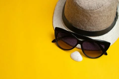 Summer accessories, sea shell, hat and sun glasses on yellow background. Summ Stock Photos