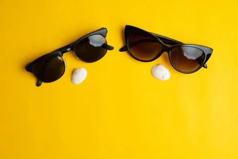 Summer accessories, sea shells and couple sun glasses on yellow background. S Stock Photos
