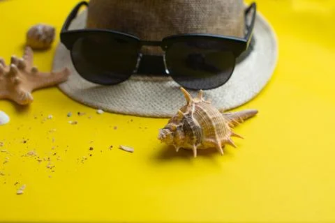 Summer accessories, sea shells, hat and sun glasses on yellow background. Sum Stock Photos