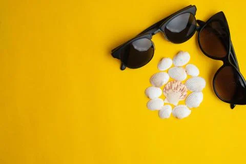 Summer accessories, shells and couple sun glasses on yellow background. Summe Stock Photos