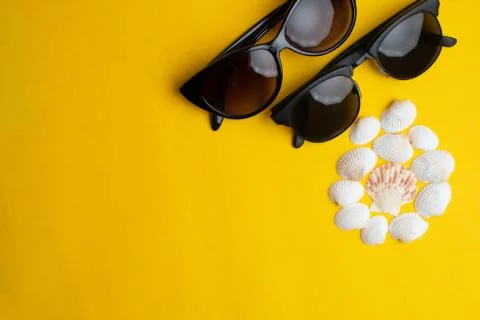 Summer accessories, shells and couple sun glasses on yellow background. Summe Stock Photos
