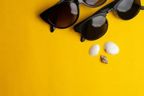 Summer accessories, shells and couple sun glasses on yellow background. Summe Stock Photos