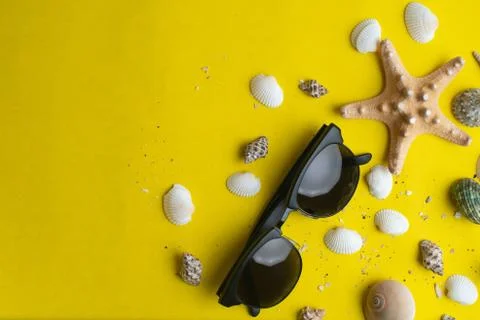 Summer accessories, shells and sun glasses on yellow background. Summer vacat Stock Photos