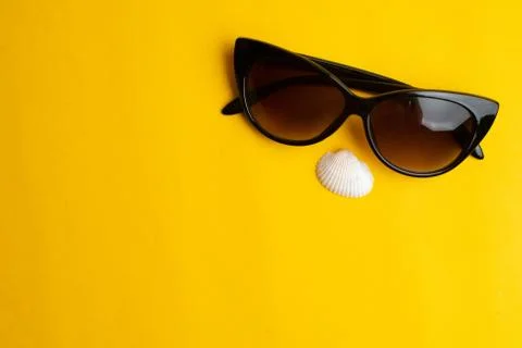 Summer accessories, shells and sun glasses on yellow background. Summer vacat Stock Photos