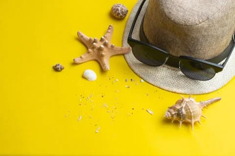 Summer accessories, shells, hat and sun glasses on yellow background. Summer  Stock Photos