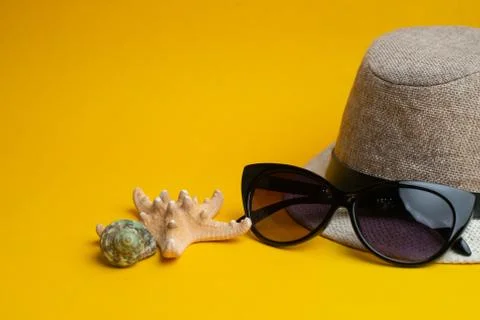 Summer accessories, shells, hat and sun glasses on yellow background.  Stock Photos