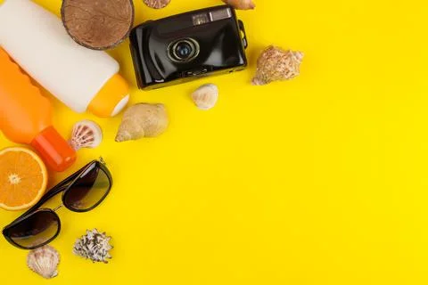 Summer accessories with shells, sun glasses, camera on a bright yellow backgr Stock Photos