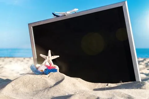 Summer background beach. Starfish, seashells, toy plane and globe near blackb Stock Photos