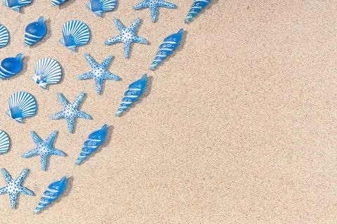 Summer background with blue seashell pattern on beach sand background. Cop... Stock Photos