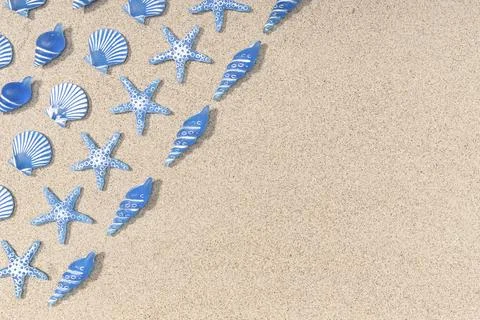 Summer background with blue seashell pattern on beach sand background. Copy Stock Photos
