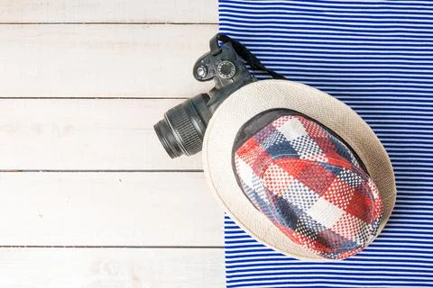 Summer background. checkered summer hat and camera on a white wooden table wi Stock Photos