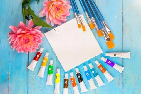 Summer background. dahlias, paints, brushes and a canvas on a blue wooden Stock Photos