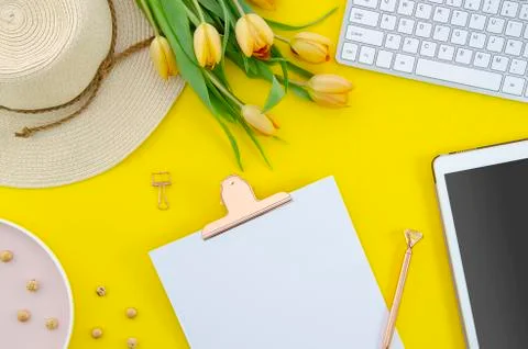 Summer background flat lay of yellow tulips with tablet keyboard and clipboard Stock Photos