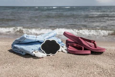 Summer background with flip flops and towel on beach Stock Photos
