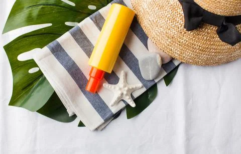 Summer background. Hat, seashells, sunscreen on a white towel. Copy space. 스톡 사진