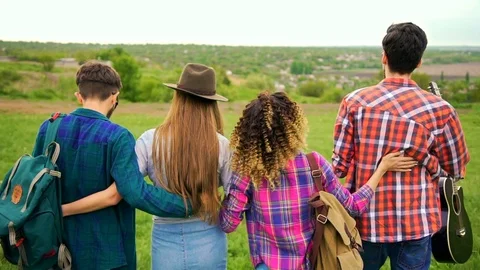 Summer background. Shot from back of four hipsters, while walking in the park Stock Footage 75694536