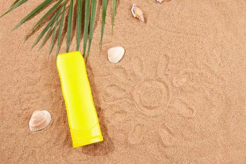 Summer background. Sunscreen, shells and palm leaves on the sand on the beach. Stock Photos