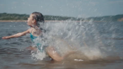 Summer beach and fun. Kids have fun and jump into the river from the sandy beach Stock Footage 344868111