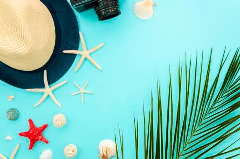 Summer beach concept flat lay. Starfishes with palm leaf and straw hat on blue Stock Photos