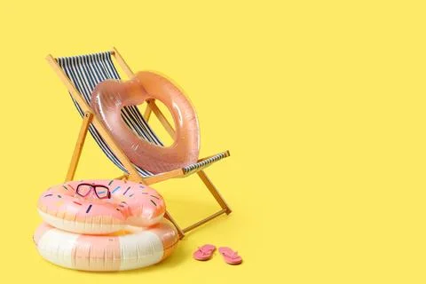 Summer beach essentials with inflatable rings and deck chair Stock Photos