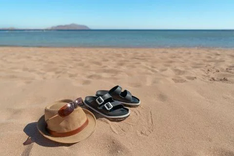 Summer beach essentials: straw hat, sunglasses, and sandals on sand Stock Photos