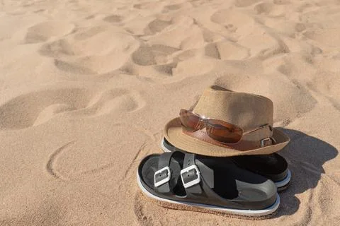 Summer beach essentials: straw hat, sunglasses, and sandals on sand Stock Photos