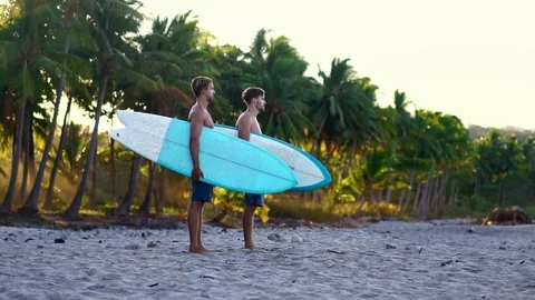 Summer beach lifestyle, young man going surfing. beautiful golden sunrise light. Stock Footage 108564286