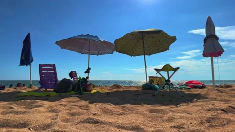 Summer beach scene with sun umbrellas chairs and deckchairs. Low angle view Stock Footage 218118347