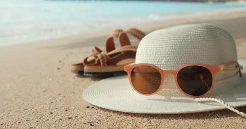 Summer beach with straw hat, sunglasses and flip flops on sandy beach background Stock Footage 173392947