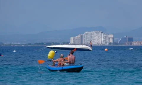 Summer beach vacation concept, two men rowing a boat Stock Photos