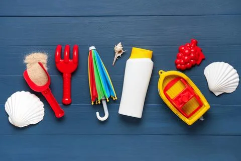 Summer beach vacation essentials with sunscreen, sand toys, and seashells on  Stock Photos
