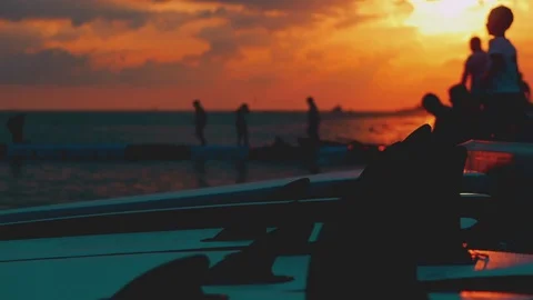 Summer beach vacation at sunset, children, boys throwing stones at the water at Stock Footage